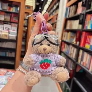 Détail de porte-clés en peluche ours mignon, avec lunettes et pull fraise, joli pendentif sac.