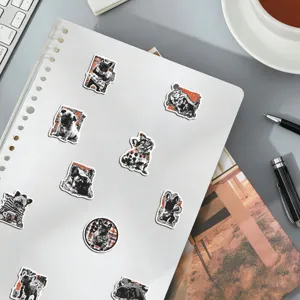 Close-up detail of trendy black and white French bulldog stickers on notebook surface.