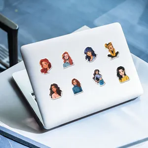 Detail view of trendy comic girl stickers decorated on a clean white laptop surface.