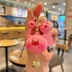 Cute pink pig keychain detail shot, featuring metal bell and portable nail clipper tools.