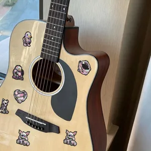 Closeup of cyberpunk mechanical animal stickers applied on an acoustic guitar surface.