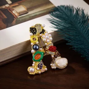 Gedetailleerd overzicht van de elegante letter A broche met parels en fonkelende strass.