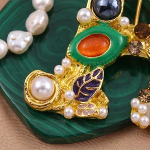 Close-up detail van vintage letter A broche met parels, strass-steentjes en kleurrijke emaille.