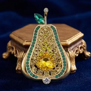 Primer plano broche vintage pera strass, metal dorado con cristales verdes y amarillos brillantes.