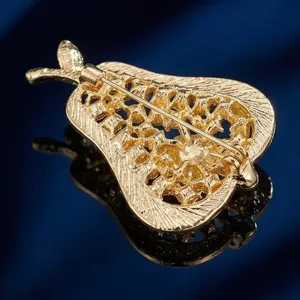 Vista en detalle de la broche pera dorada, elegante accesorio de joyería para mujer.