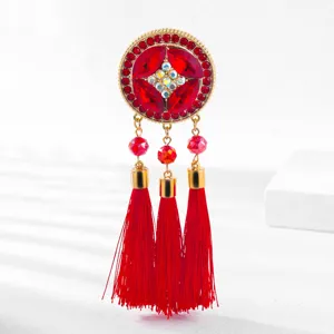 Primo piano dettagliato di una spilla vintage in stile cinese con nappa in cristallo rosso.