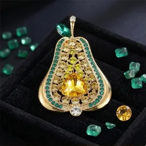Primer plano del broche vintage en forma de pera con cristales brillantes y tono dorado.
