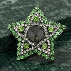 Gedetailleerde close-up van een luxe vintage stervormige broche versierd met groene kristallen.