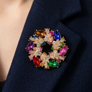 Detailaufnahme der bunten Strass Blumenkranz Brosche an einer eleganten dunklen Jacke.