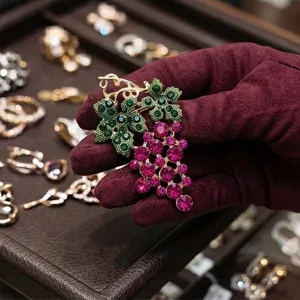 Detailed close-up of vintage grape brooch with sparkling rhinestones on a elegant display tray.