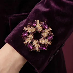 Detailansicht der eleganten Vintage lila Strass Blumenkranz Brosche am Samtärmel.
