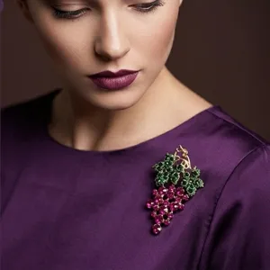 Close-up detail of luxury vintage grape rhinestone brooch on model, elegant crystal jewelry.