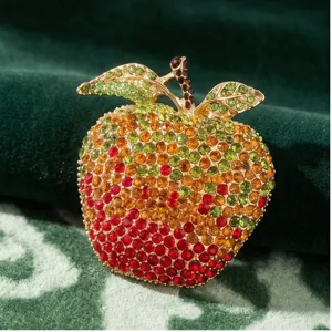 Close-up view of the sparkling rhinestone apple brooch detail, showcasing vibrant multicolored crystals.