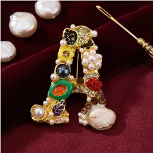 Close-up opname van een luxe letter A broche versierd met parels en kleurrijke steentjes.