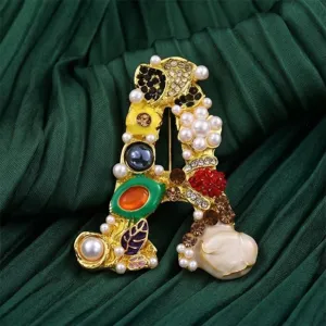 Gedetailleerd overzicht van luxe letter A broche met glinsterende strass-stenen en parels.