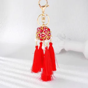Detailed view of red rhinestone embroidered ball keychain with multi-layer tassels.