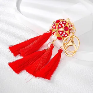Detailed shot of Chinese style rhinestone embroidered ball keychain with vibrant red tassels.