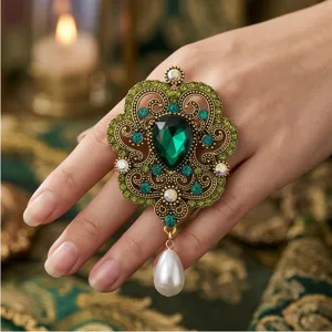 Anillo llamativo barroco vintage con esmeralda y colgante de perla, detalle de palacio.