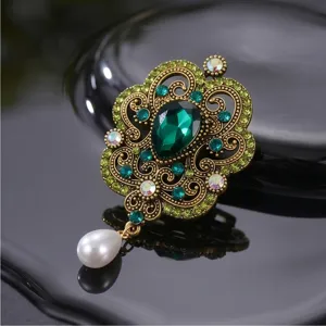 Detalle de broche vintage barroco con estrás verde, diseño elegante de metal dorado.