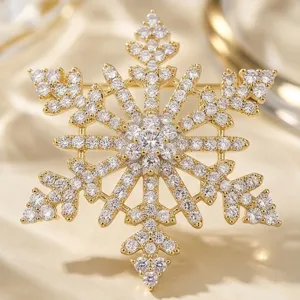 Broche flocon de neige dorée détaillée ornée de cristaux scintillants pour tenue chic.