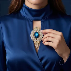 Nahaufnahme der goldenen Vintage-Brosche mit blauen Strasssteinen und feinen Details.