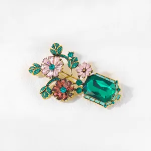 Detailed view of a vintage crystal vase brooch featuring sparkling green and pink rhinestones.