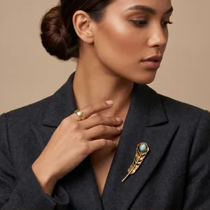 Close-up detail of vintage gold feather brooch with turquoise stone, worn on dark grey blazer.