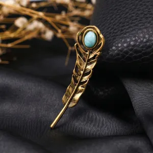 Vintage feather brooch detail showing the exquisite gold-toned metal texture and turquoise stone.