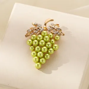 Primo piano di una graziosa spilla uva con perle e strass, dettaglio bijoux in lega.