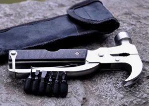 Detail view of the multi-functional hammer tool and bits arranged on a rugged stone background.