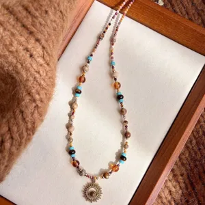 Detail view of a vintage multi-color beaded necklace featuring a unique sun metal pendant.