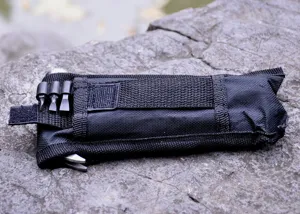 Detailed view of black nylon multi-tool pouch with screwdriver bits on rock background.