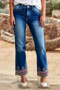 Details of women's dark blue straight denim jeans featuring colorful geometric cuff embroidery.