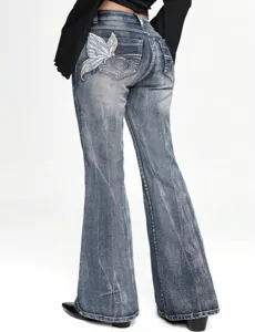 Detail of women's washed blue flare jeans featuring intricate butterfly embroidery on the back pocket.