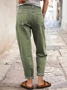Détail de jean vert à revers montrant une coupe ample, des poches arrière et un style urbain.