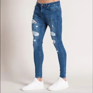 Close-up detail of men's distressed blue skinny denim jeans showing ripped knee texture.