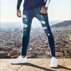 Close-up detail shot of men's slim fit distressed skinny jeans in urban outdoor setting.