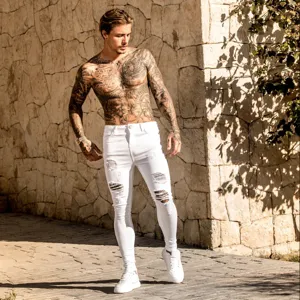 Outdoor detail view of white slim-fit ripped skinny denim pants showcasing textured distressed knees.