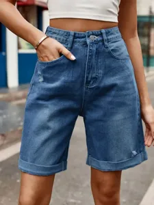 Close-up detail of women's high-waisted denim shorts with rolled cuffs and classic blue wash.