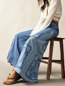 Detailed view of bohemian wide-leg denim pants featuring intricate floral side patterns.
