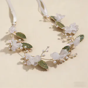 Detailed close-up of exquisite floral hair vine with white chiffon flowers and green leaves.