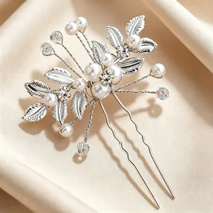 Détail gros plan d'épingle à cheveux de mariée en U avec perles et feuilles.