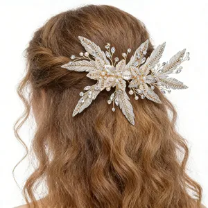 Bridal hair clip detail showcasing sparkling rhinestones, pearls, and metallic leaf design.