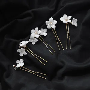 Détail de pinces à cheveux en céramique blanche, élégants accessoires de mariée dorés.