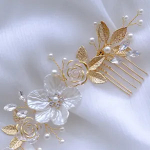 Primo piano sui dettagli del pettine per capelli da sposa dorato con fiori bianchi.