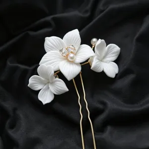 Gros plan d'épingle à cheveux fleur en céramique blanche artisanale avec perles pour mariée.