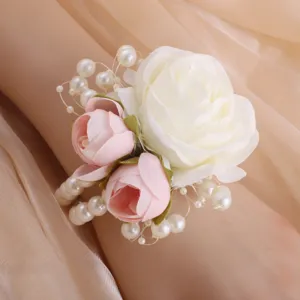 Close-up detail of wedding wrist corsage featuring white rose and faux pearls for bride.