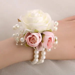 Close-up detail of wedding bridesmaid wrist flower with white pink roses and pearl bracelet.