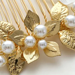 Close-up detail of exquisite gold bridal hair comb featuring delicate pearl and leaf decor.