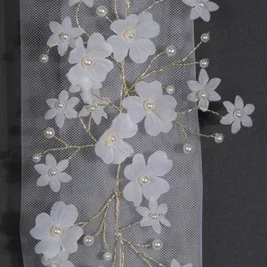 Handmade bridal hair accessory with white fabric flowers, pearls, and gold wire mesh.